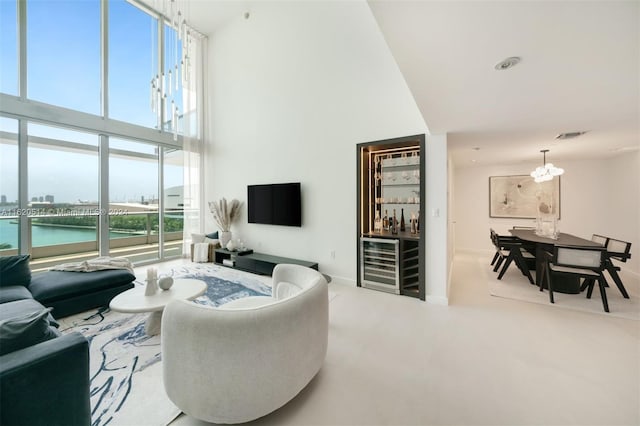 living room featuring a towering ceiling, a water view, a notable chandelier, and plenty of natural light