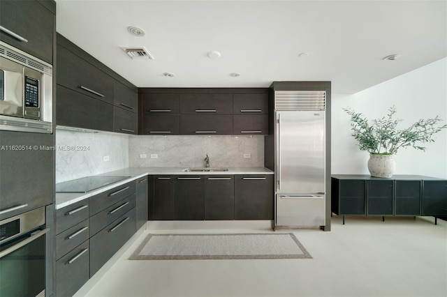 kitchen featuring visible vents, built in appliances, light countertops, decorative backsplash, and a sink