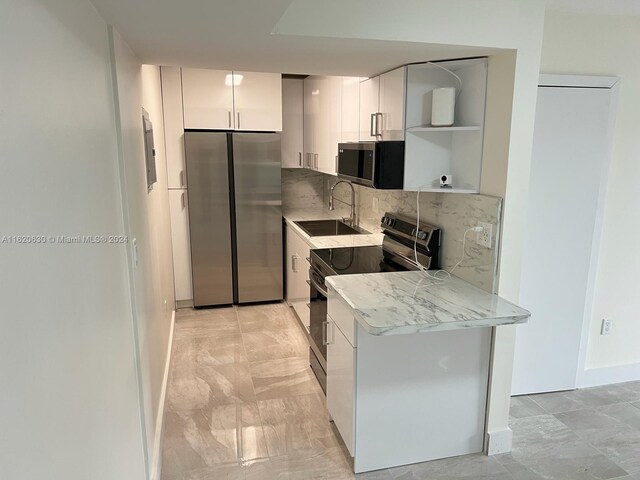 kitchen with backsplash, sink, appliances with stainless steel finishes, and light tile patterned floors