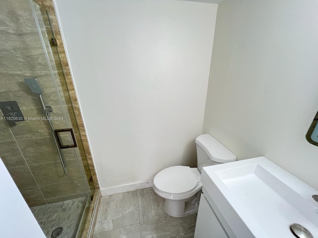 bathroom featuring vanity, a shower with door, tile patterned flooring, and toilet