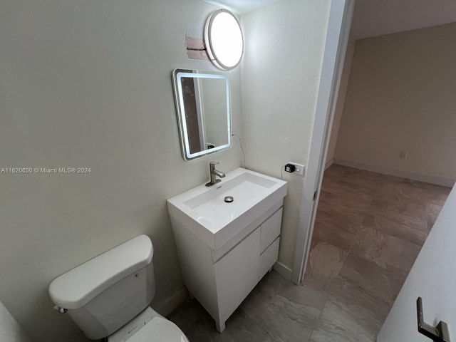 half bath with vanity, toilet, and baseboards