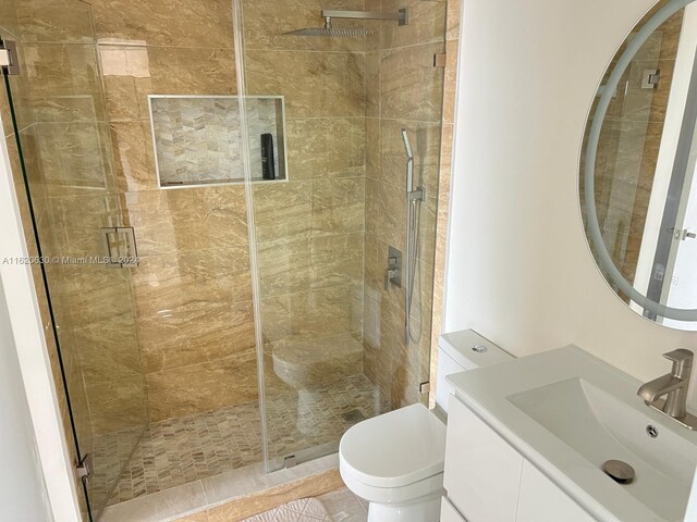 bathroom featuring a shower with shower door, vanity, and toilet