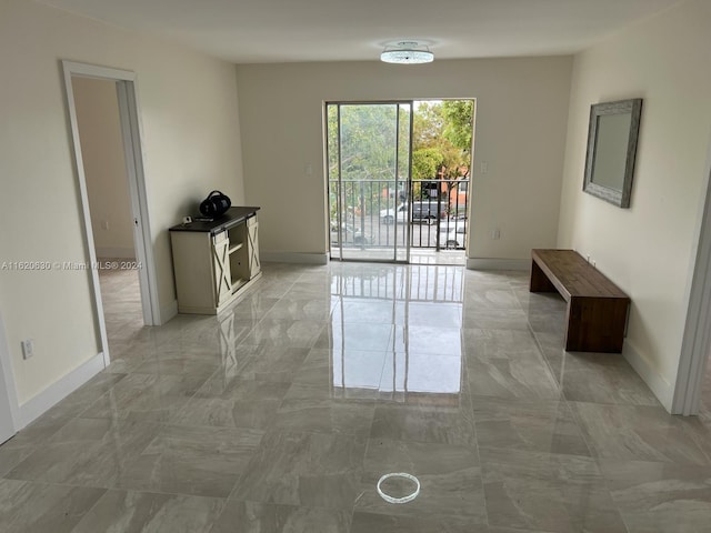 spare room featuring marble finish floor and baseboards