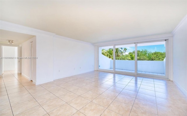 empty room featuring light tile patterned flooring and ornamental molding