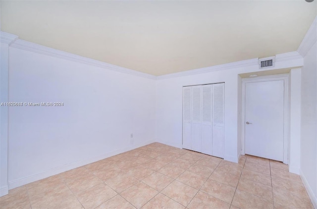 unfurnished bedroom featuring light tile patterned flooring, a closet, and ornamental molding