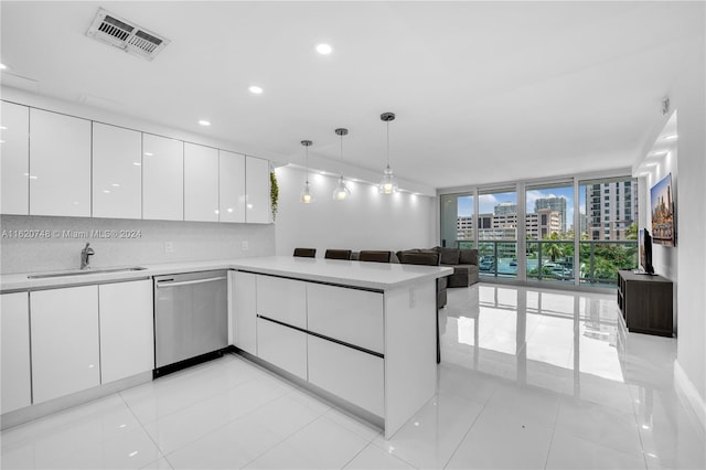 kitchen featuring hanging light fixtures, stainless steel dishwasher, sink, and white cabinets