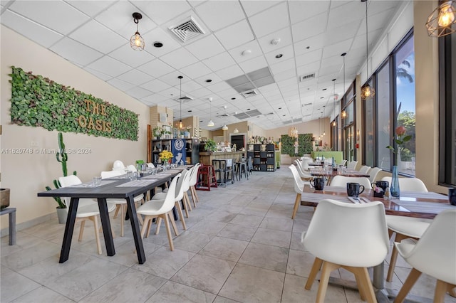 tiled dining space featuring a drop ceiling