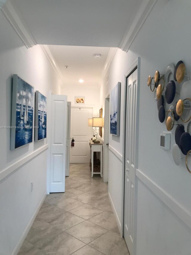 corridor featuring crown molding and light tile patterned floors