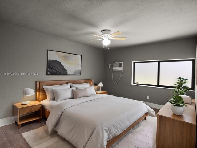 bedroom with a textured ceiling, a wall mounted AC, ceiling fan, and hardwood / wood-style floors