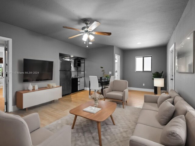 living room featuring a textured ceiling, ceiling fan, and light hardwood / wood-style floors