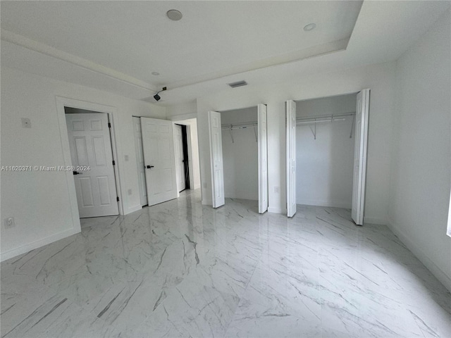 unfurnished bedroom with multiple closets and light tile patterned floors