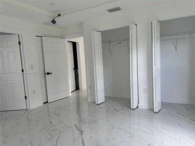 unfurnished bedroom with two closets and light tile patterned flooring