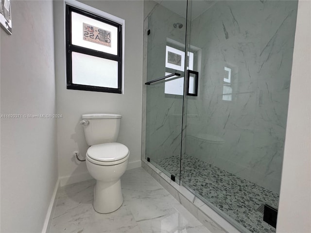 bathroom featuring a shower with shower door and toilet