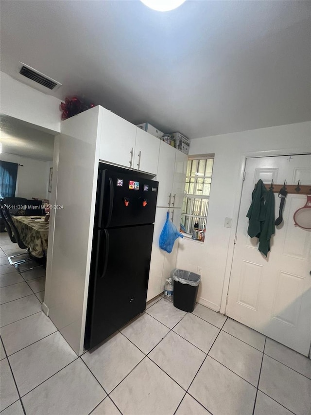 kitchen featuring black refrigerator, white cabinets, and light tile patterned floors