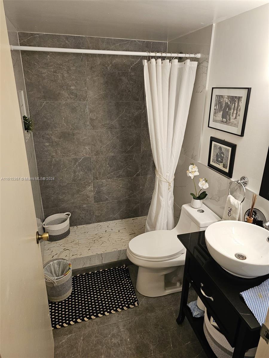 bathroom featuring tile patterned flooring, curtained shower, toilet, and vanity