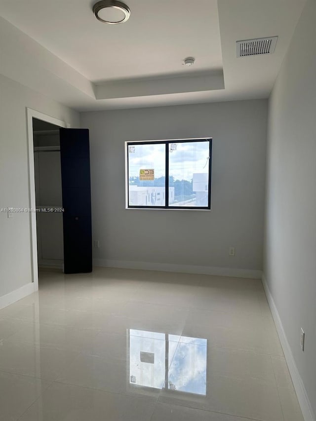 unfurnished room featuring light tile patterned floors and a tray ceiling