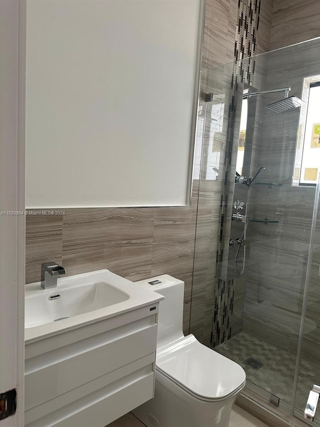 bathroom with a shower with shower door, vanity, toilet, and tile walls