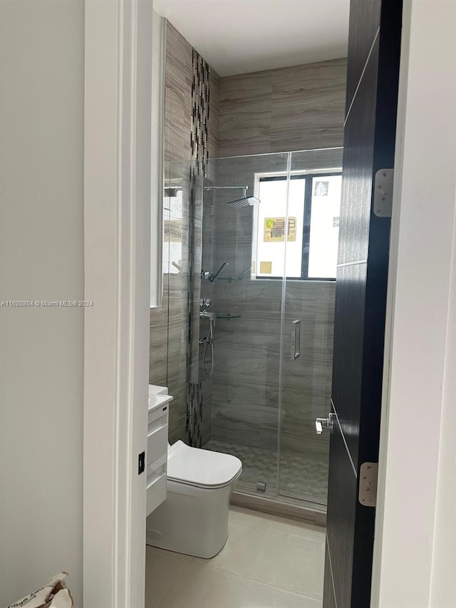 bathroom with a shower with shower door, vanity, tile patterned flooring, and toilet