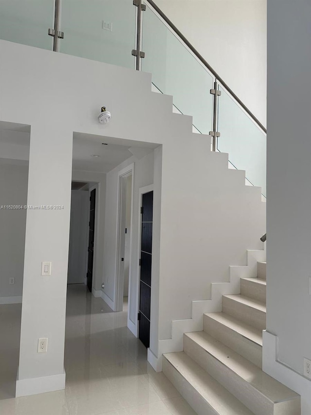 stairway featuring a towering ceiling