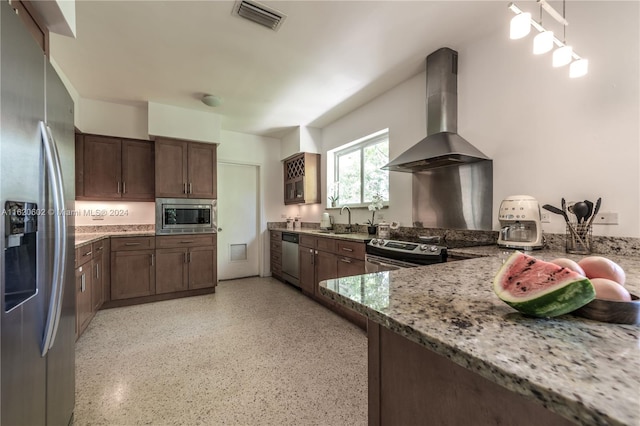 kitchen with light stone counters, sink, wall chimney exhaust hood, appliances with stainless steel finishes, and dark brown cabinetry