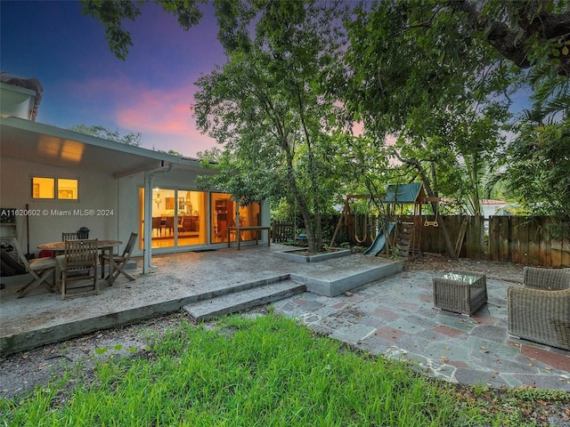 yard at dusk with a patio and a playground