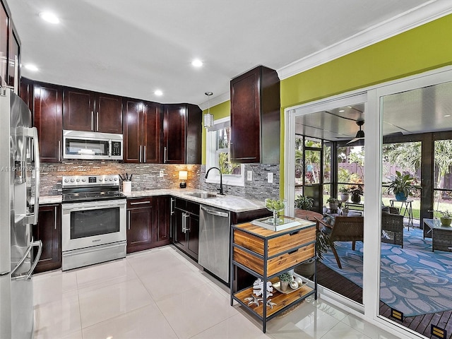 kitchen featuring tasteful backsplash, light tile patterned floors, appliances with stainless steel finishes, a healthy amount of sunlight, and sink