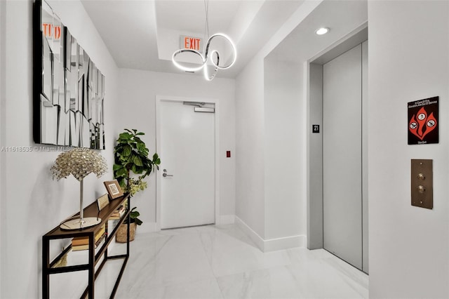 hall with elevator and a notable chandelier