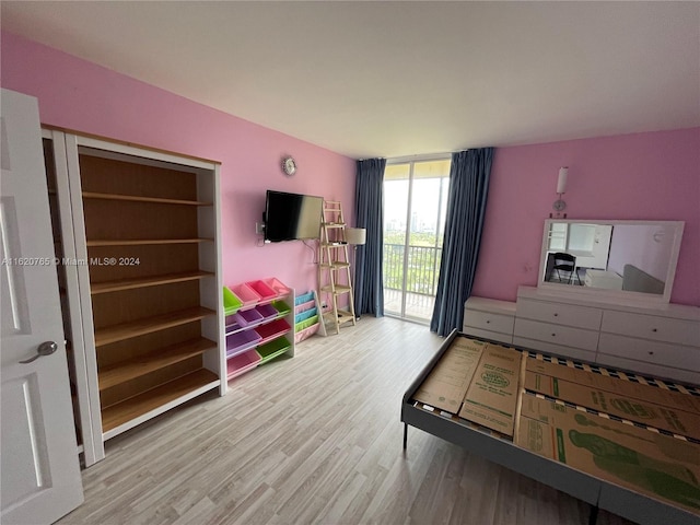 bedroom featuring access to outside, expansive windows, and wood-type flooring