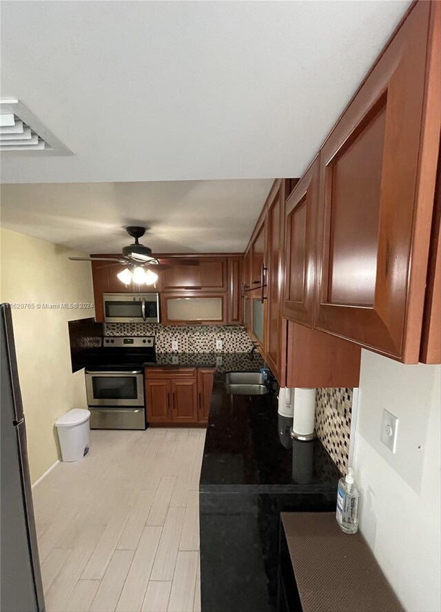 kitchen with ceiling fan, light wood-type flooring, sink, appliances with stainless steel finishes, and backsplash