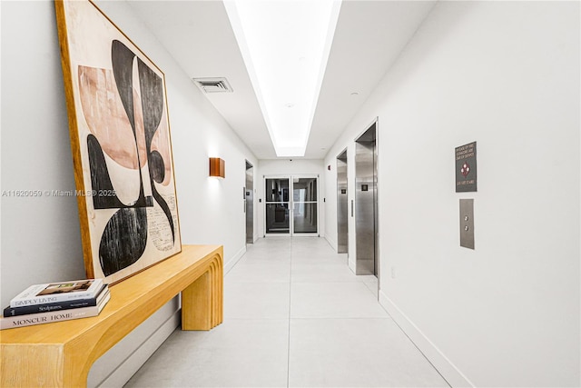 corridor with visible vents, baseboards, and light tile patterned flooring