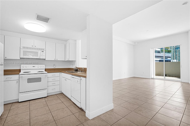 kitchen with white appliances, visible vents, white cabinetry, a sink, and light tile patterned flooring