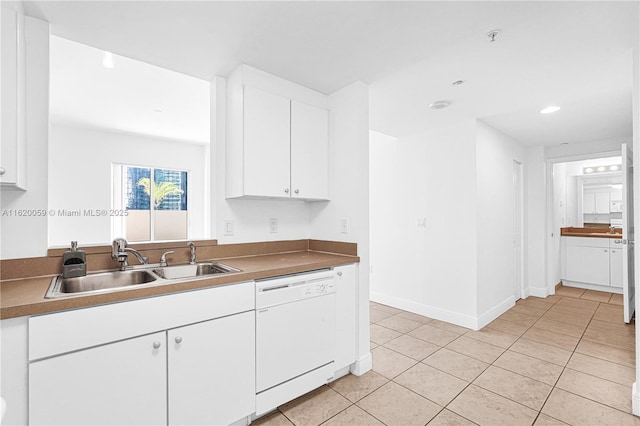 kitchen featuring light tile patterned flooring, a sink, baseboards, white cabinets, and dishwasher