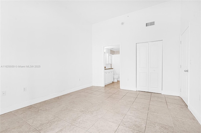 unfurnished bedroom featuring light tile patterned floors, a closet, visible vents, high vaulted ceiling, and baseboards