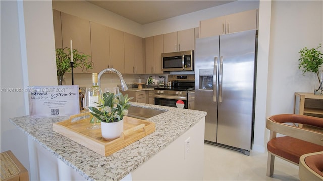 kitchen with kitchen peninsula, sink, light stone countertops, and appliances with stainless steel finishes