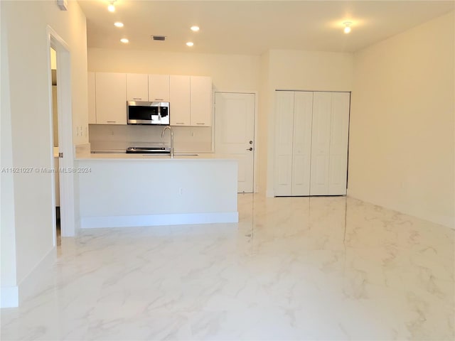 kitchen with white cabinets, kitchen peninsula, and light tile patterned flooring