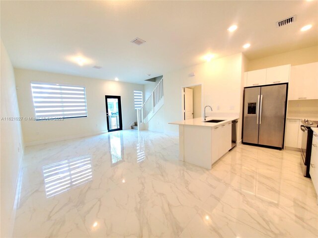 kitchen with stainless steel appliances, sink, white cabinets, and kitchen peninsula