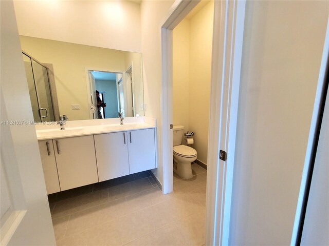 bathroom featuring tile patterned floors, vanity, toilet, and a shower with door