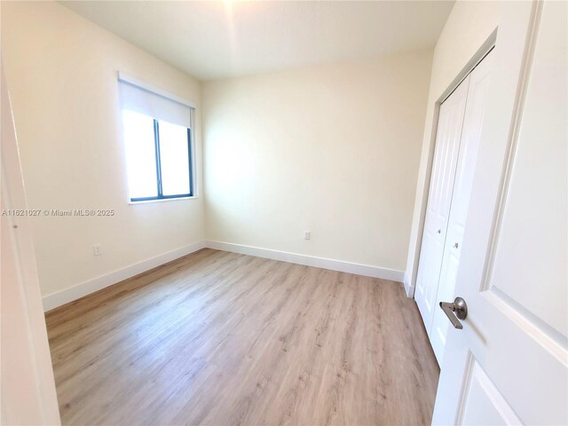 unfurnished bedroom featuring light wood-type flooring and a closet