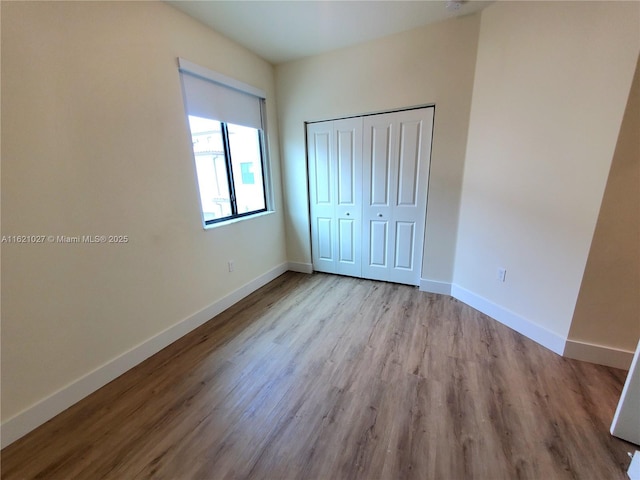 unfurnished bedroom with light wood-type flooring and a closet