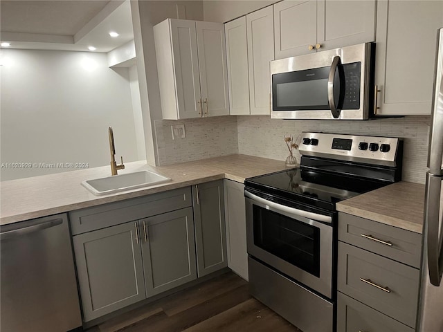 kitchen with gray cabinets, stainless steel appliances, a sink, and light countertops