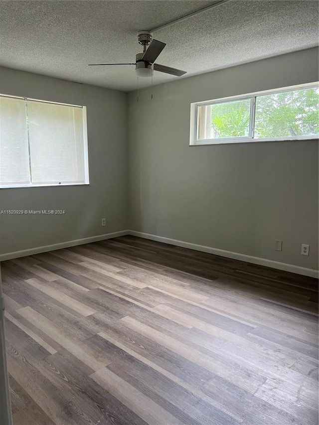 empty room with a textured ceiling, a ceiling fan, light wood-style flooring, and baseboards