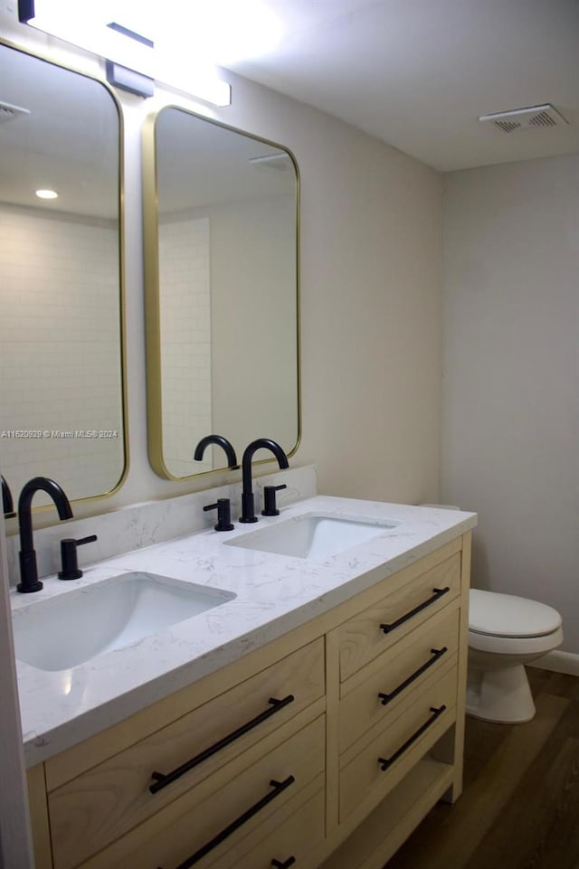 full bath featuring double vanity, visible vents, toilet, and a sink