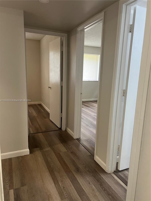 corridor with baseboards and dark wood-type flooring