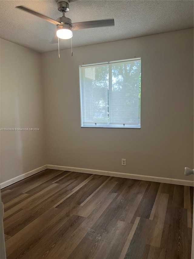 spare room with baseboards, dark wood finished floors, and a textured ceiling