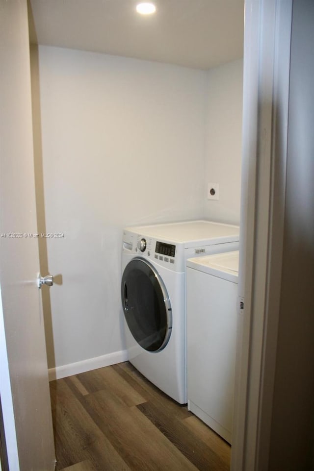 clothes washing area with dark wood-type flooring and washer and clothes dryer