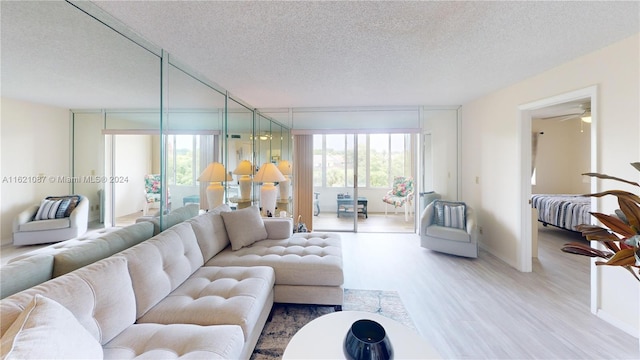 living room with a textured ceiling, hardwood / wood-style floors, ceiling fan, and a wealth of natural light