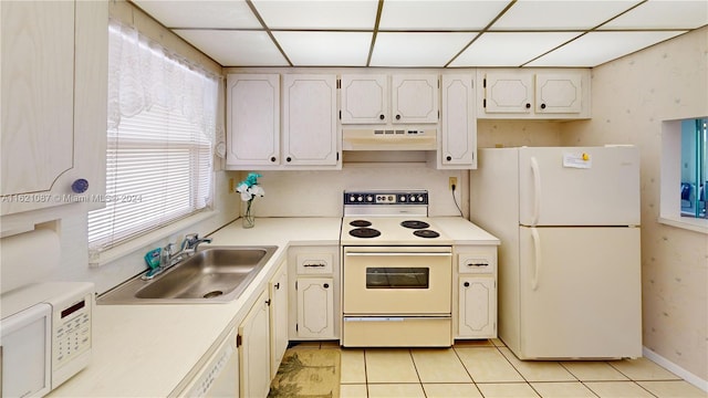 kitchen with a paneled ceiling, white appliances, sink, and light tile patterned floors