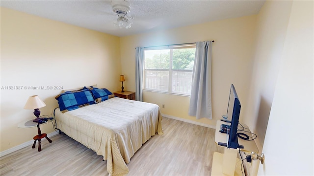 bedroom with ceiling fan, a textured ceiling, and light hardwood / wood-style flooring