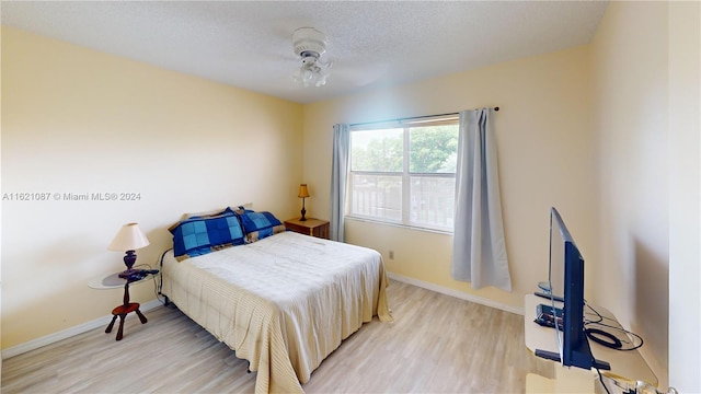 bedroom with ceiling fan, a textured ceiling, and light hardwood / wood-style flooring