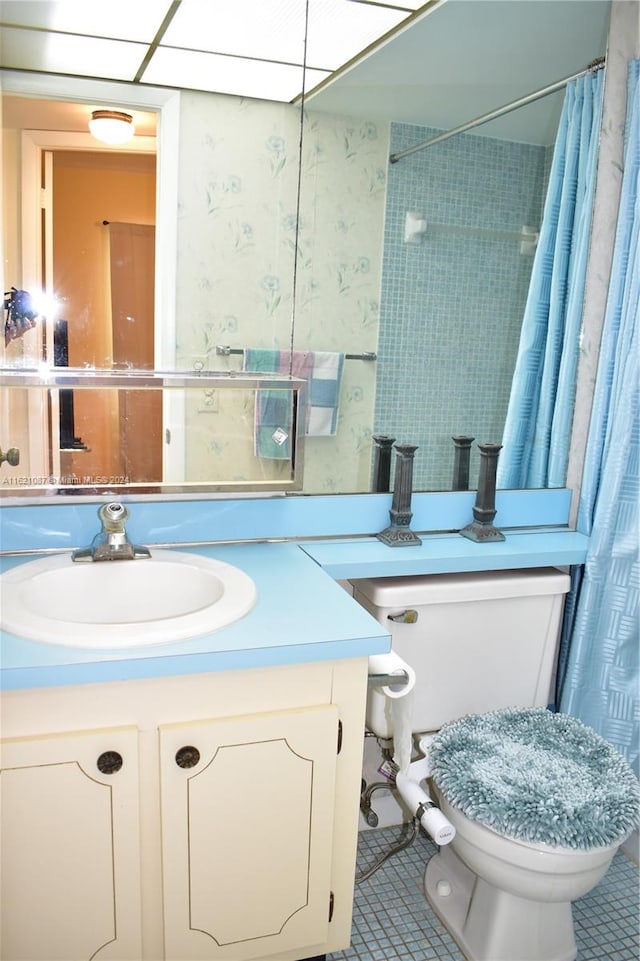 bathroom with a shower with shower curtain, tile patterned floors, vanity, and toilet